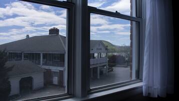 A view through a window with a view of a building with a balcony and a covered area.