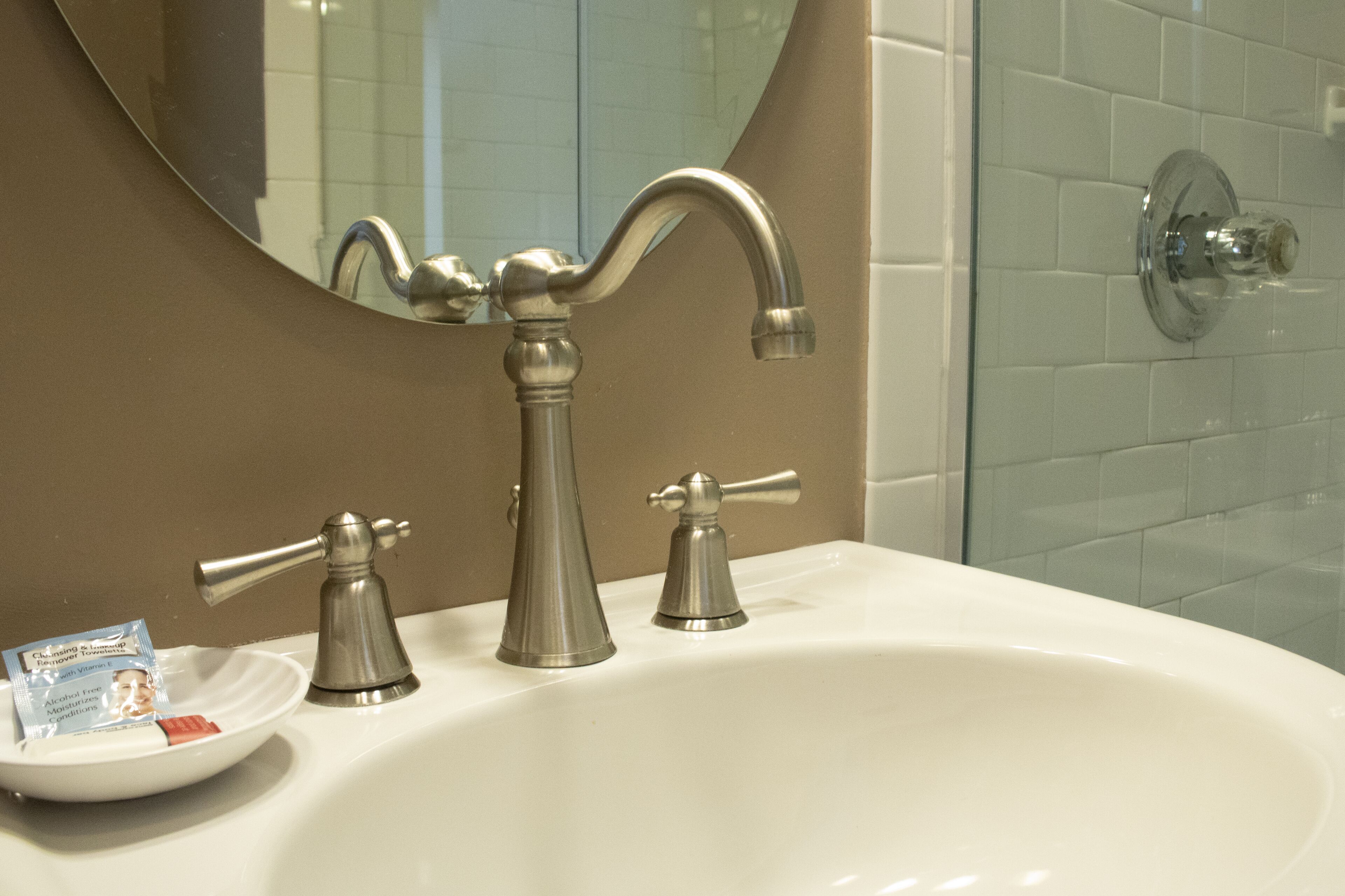 A bathroom with a white sink, two faucets, and a mirror.