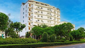 A multi-story hotel with a white facade, multiple balconies, and a well-maintained garden area. - Collection O Howard Square Boutique Hotel (Bangkok)