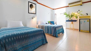 A hotel room with two beds, a desk, a chair, a plant, and a refrigerator. - Collection O Howard Square Boutique Hotel (Bangkok)