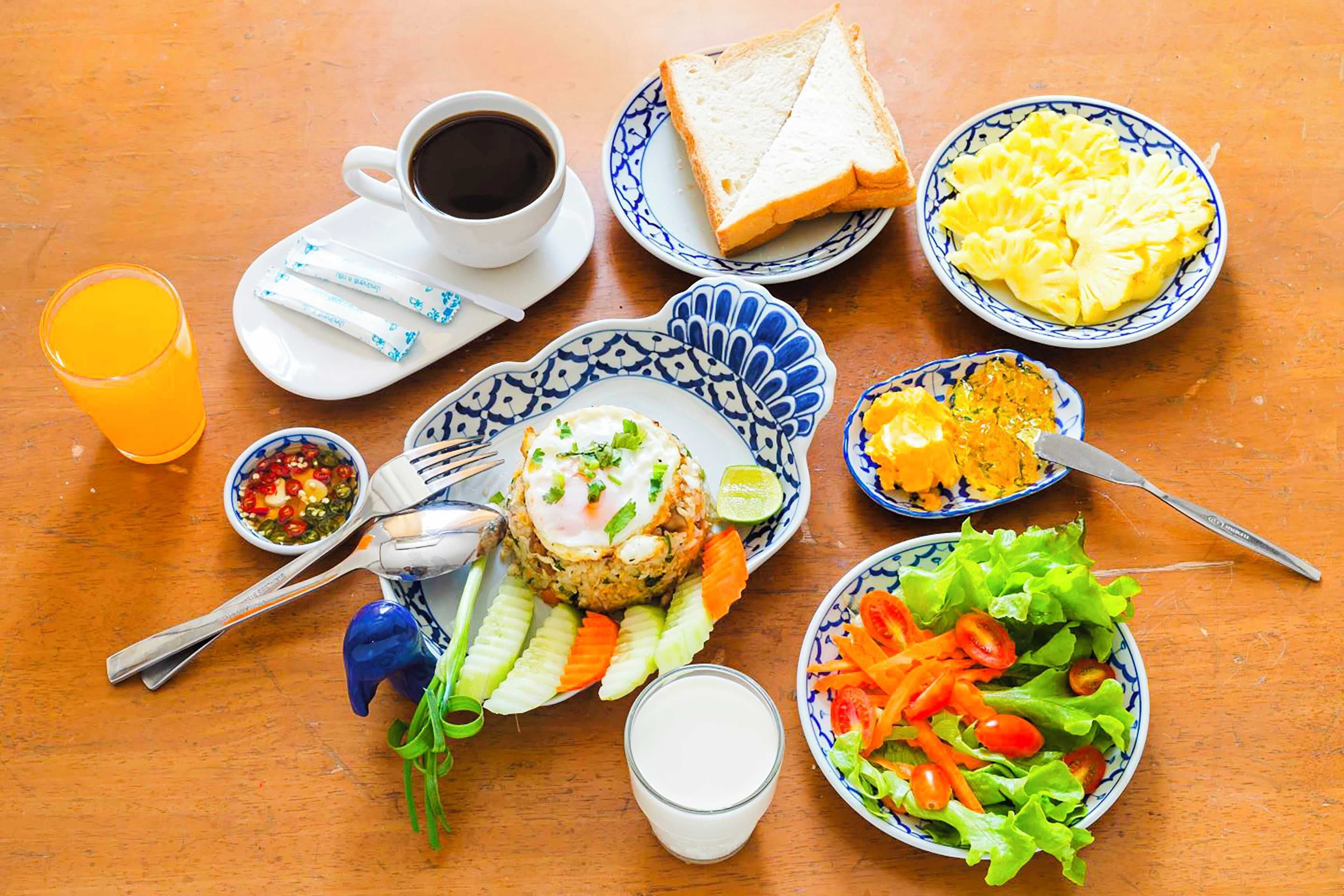 Una mesa con diferentes alimentos, como tostadas, huevos, una ensalada y una bebida.