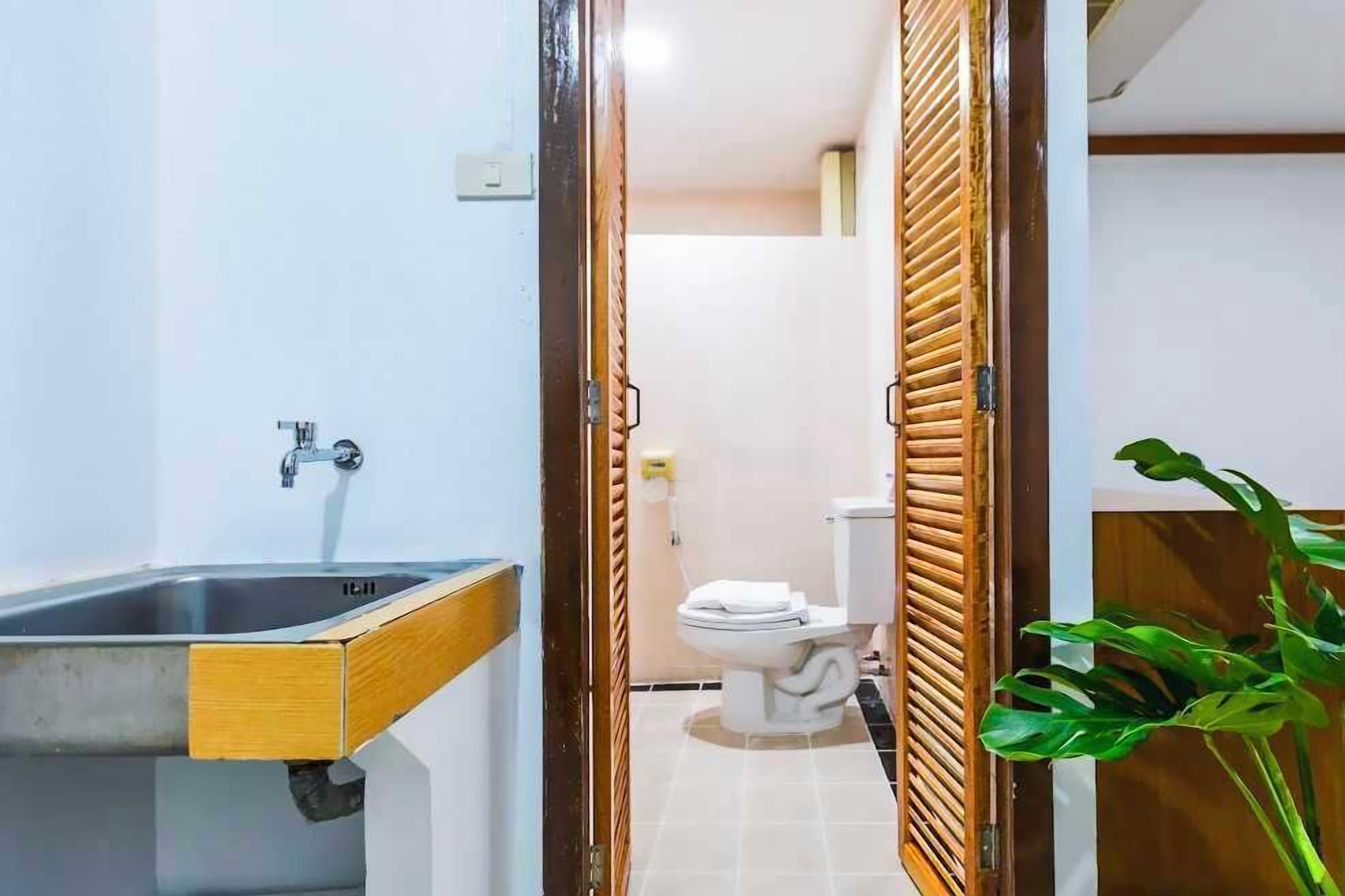 A bathroom with a wooden vanity, a toilet, and a sink.