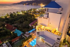 A high-rise hotel with a rooftop pool, a tennis court, and a view of the sea at sunset. - Andaman Beach Suites Hotel (Patong)