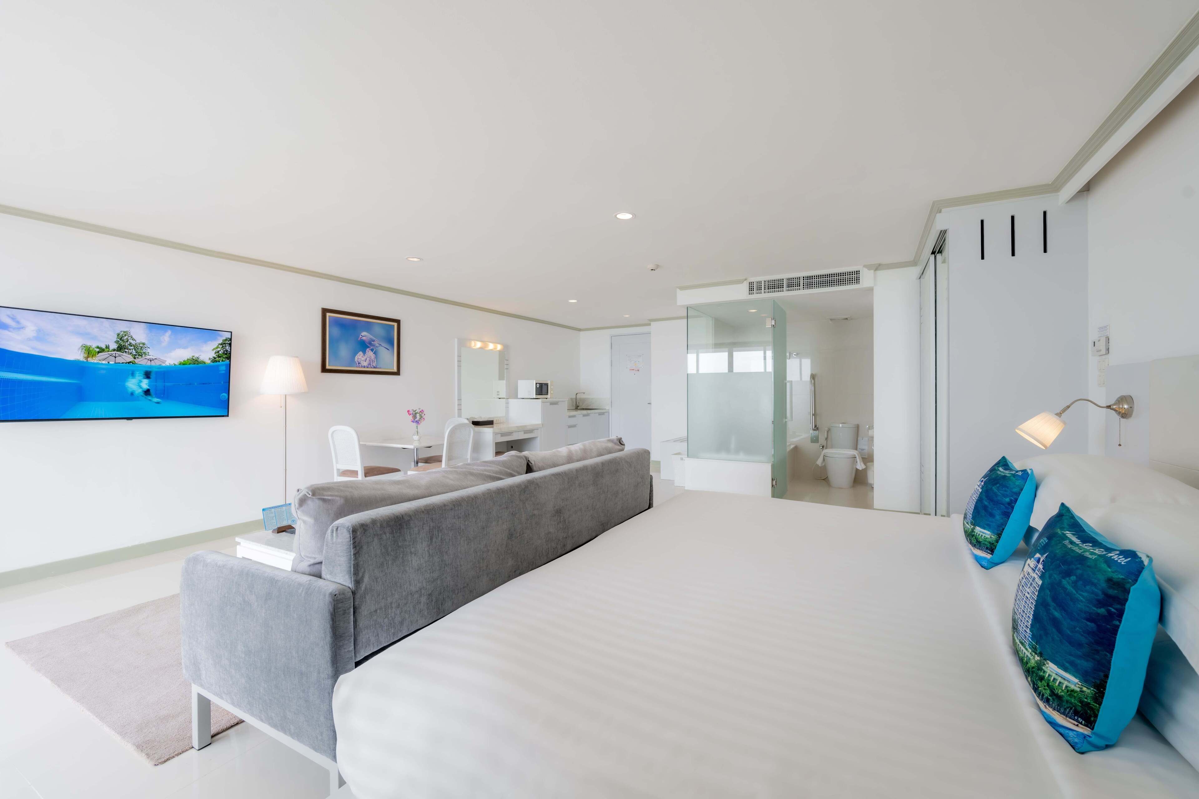 Une chambre d’hôtel moderne équipée d’un grand lit, d’un canapé, d’un bureau et d’une télévision.