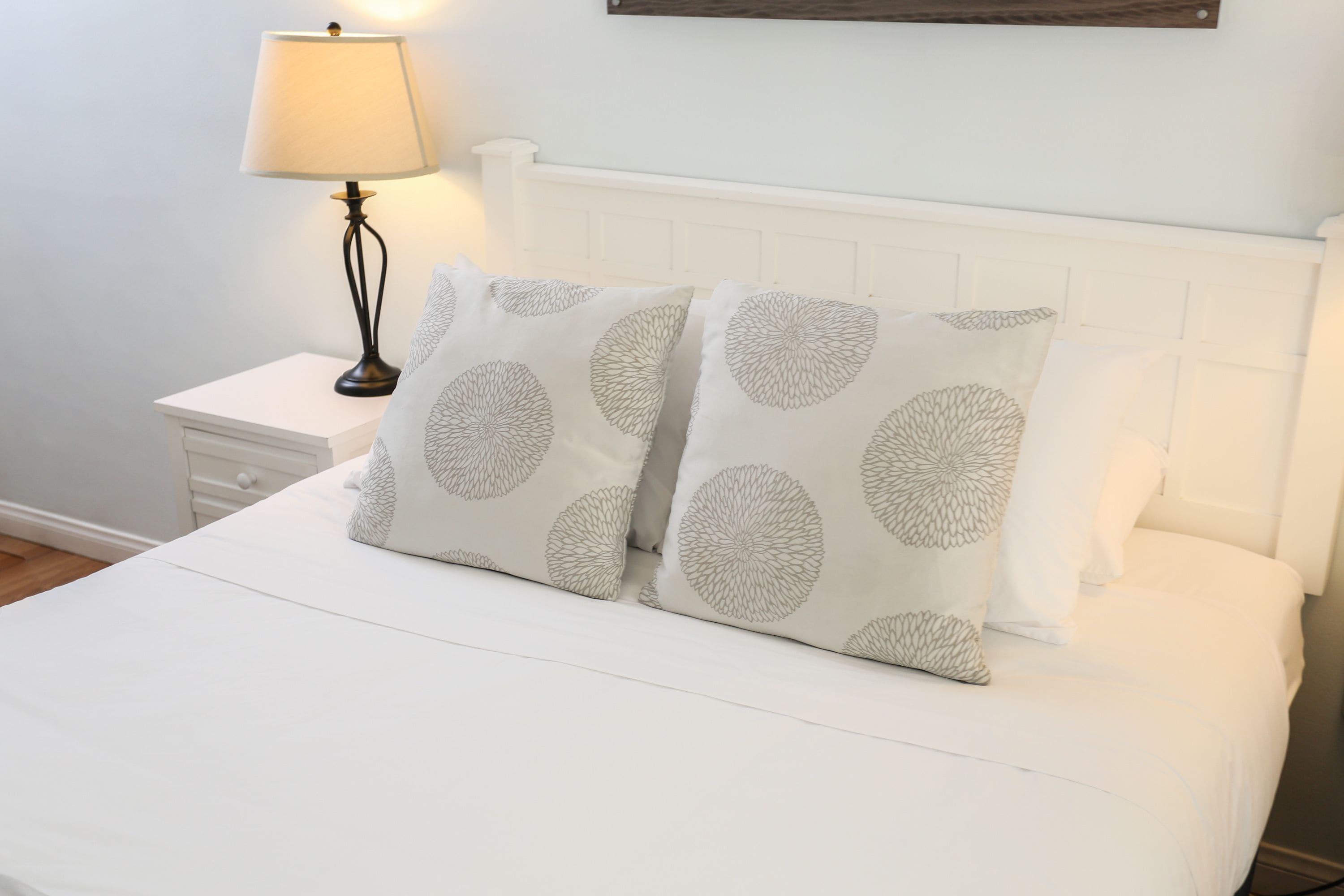 Een net opgemaakt bed met witte lakens en decoratieve kussens met cirkelmotieven.