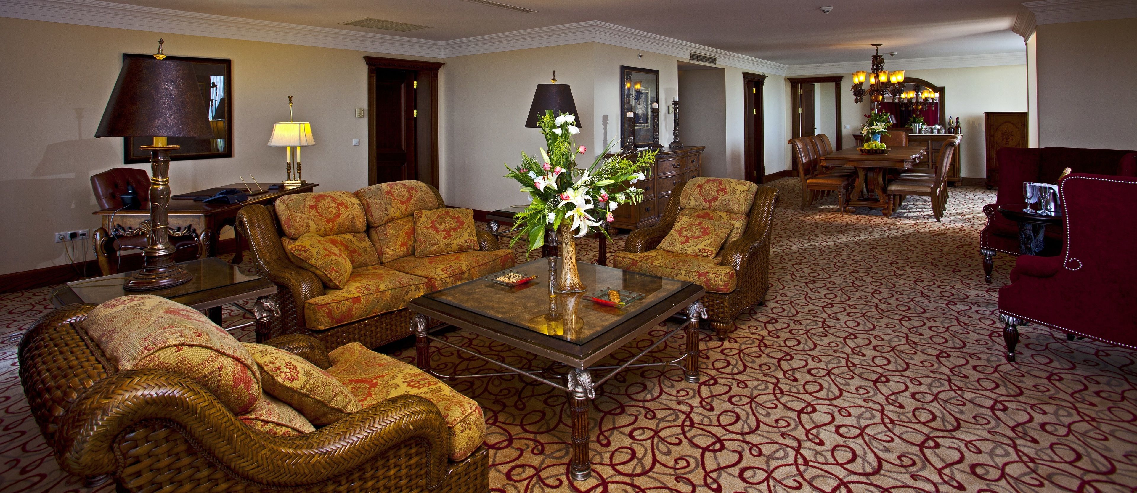 A spacious living room with a large sofa, a coffee table, and a dining area with a chandelier.