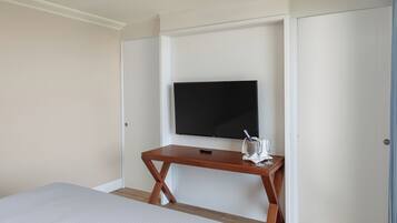 Una habitación de hotel con una cama, un escritorio de madera, un televisor de pantalla plana y una puerta.