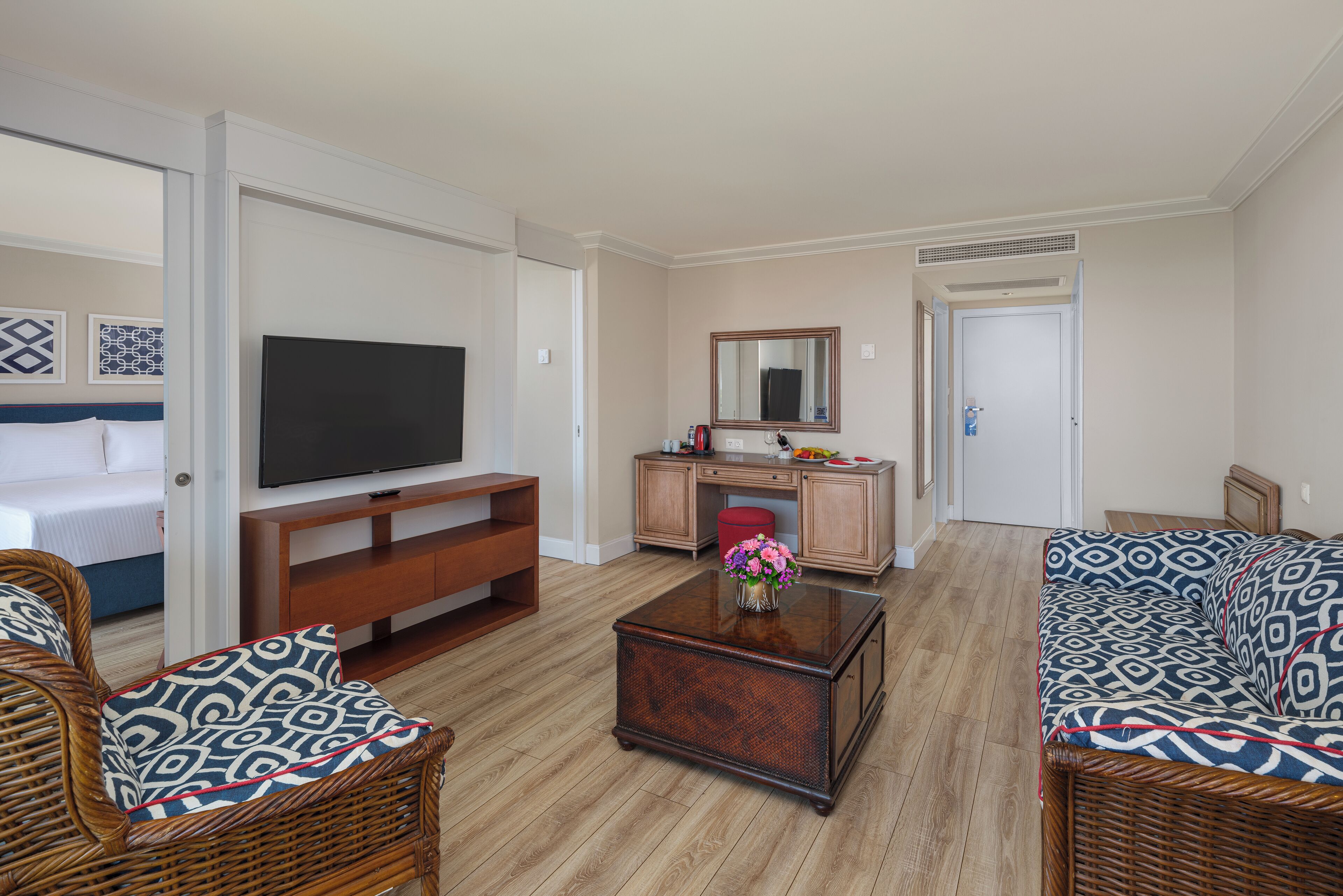 Una sala de estar con televisor, una mesa de centro y dos sofás estampados.