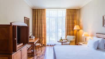 Una camera d'albergo con un letto, una scrivania, una sedia, una lampada e una televisione.
