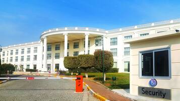 A large, white building with a central courtyard, a security office, and a sign indicating "IC Hotels."