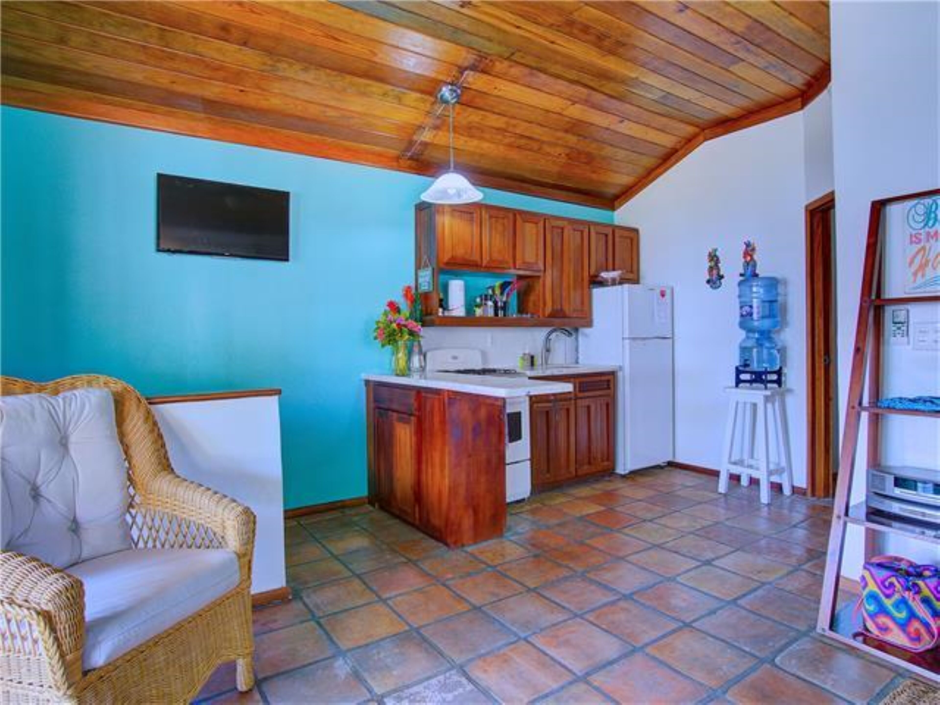 A compact kitchen with wooden cabinets, a white refrigerator, and a water dispenser.