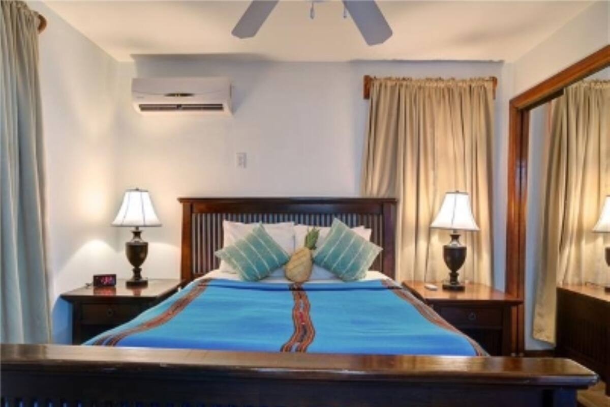 Une chambre à coucher comprenant un lit, deux tables de chevet, une commode, un miroir et un ventilateur de plafond.