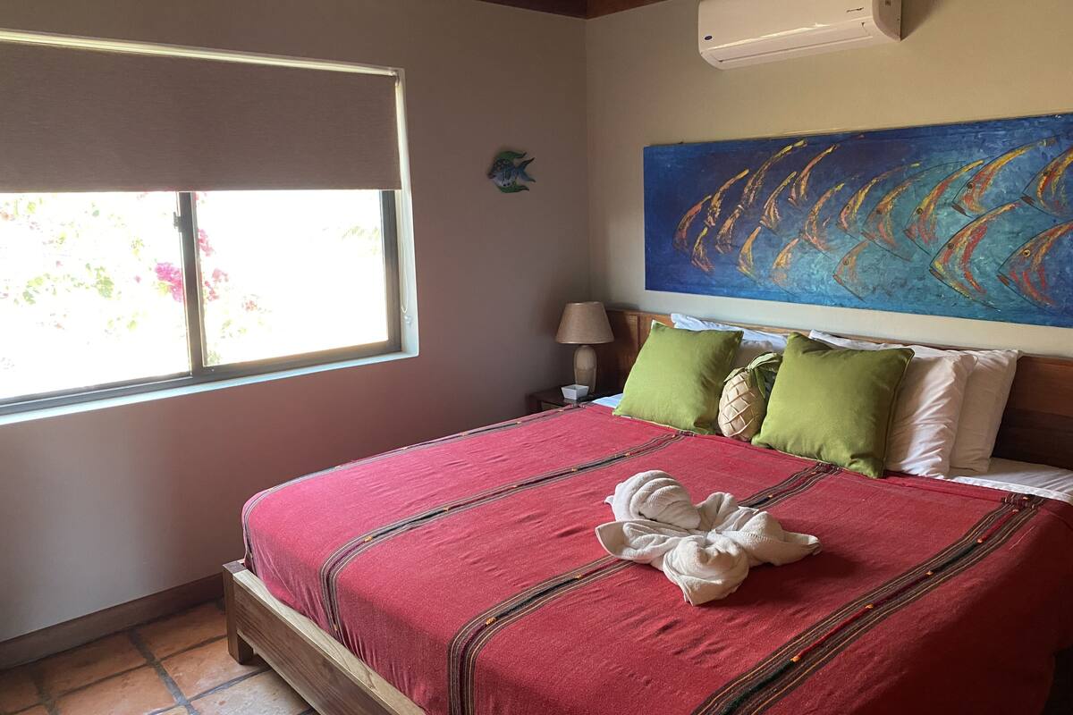 Une chambre d’hôtel avec un lit, une fenêtre, un tableau et un appareil de climatisation.