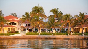 Ein Hotel am Wasser mit mehreren Gebäuden, Palmen und einem Kanal.