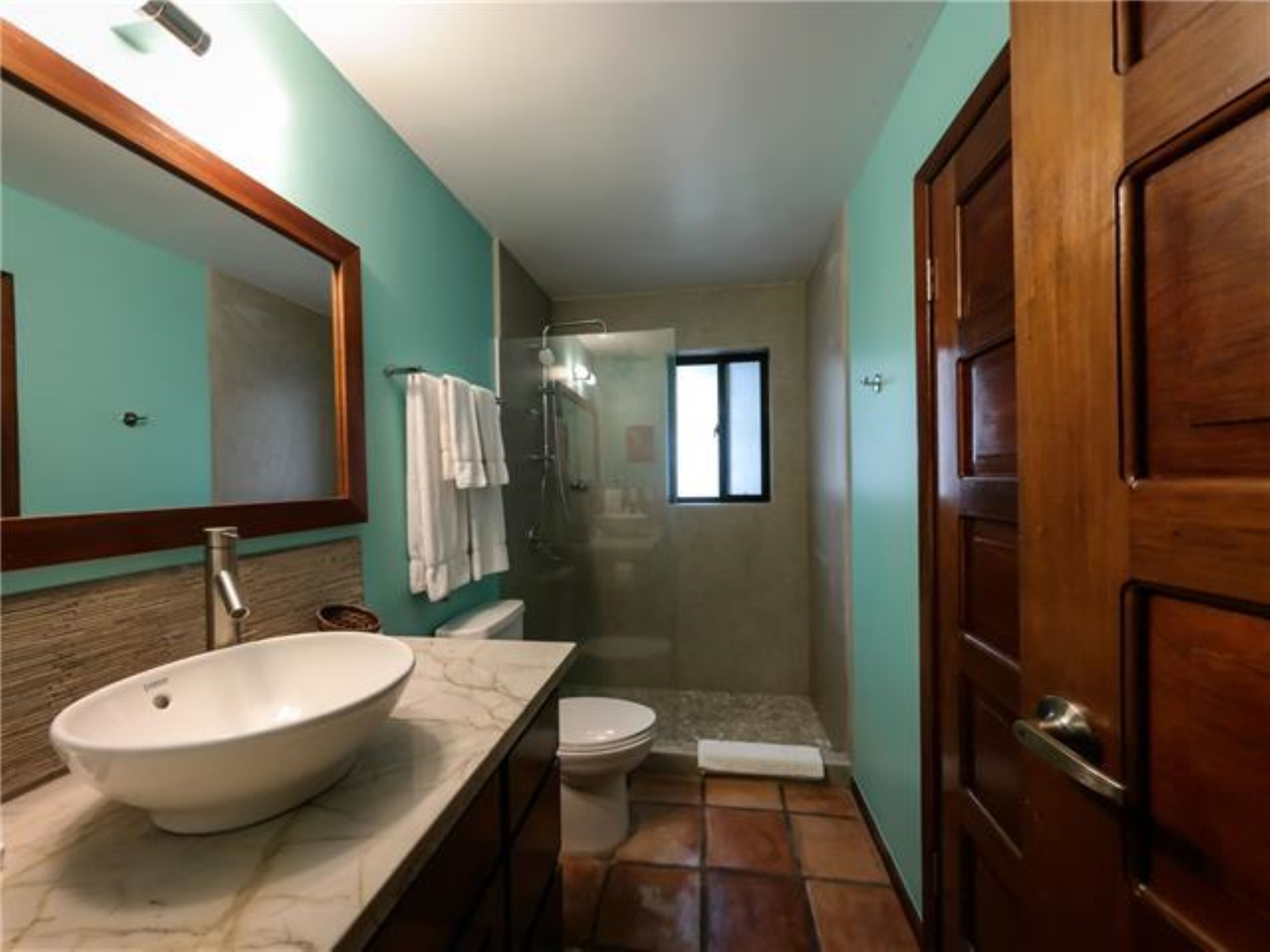 A bathroom with a large sink, toilet, and shower.