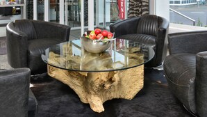 A modern lobby with leather sofas, a glass coffee table with a wooden base, and a fruit bowl. - Hotel UHU Garni Köln (Cologne)