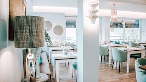 A modern dining area with tables and chairs, a large woven lamp, and decorative wall art. - Hotel Concorde (Bad Soden am Taunus)