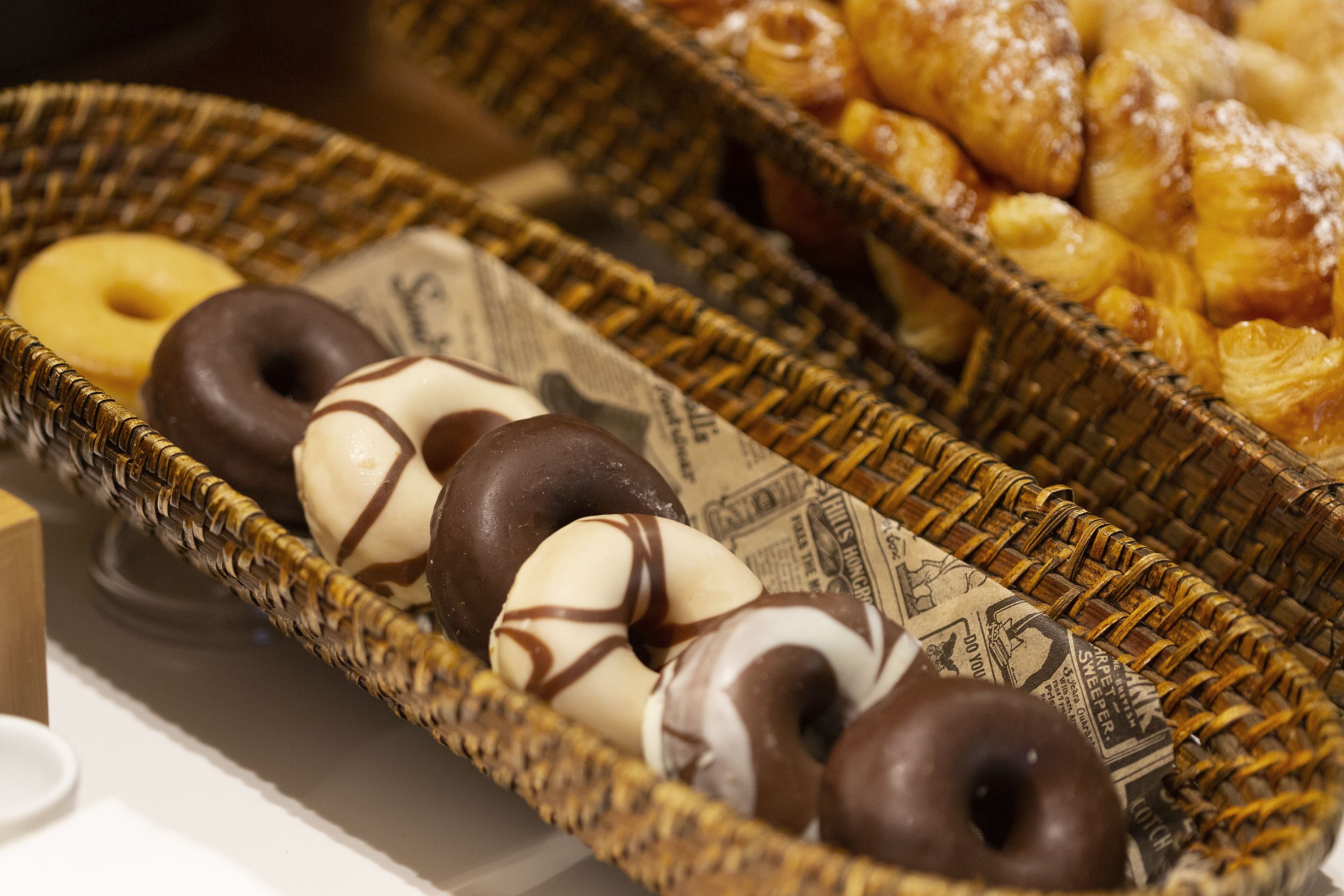A wicker basket filled with donuts and pastries.