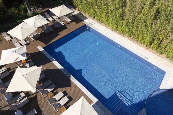 Relax by the pool surrounded by lush greenery and comfortable lounge chairs.