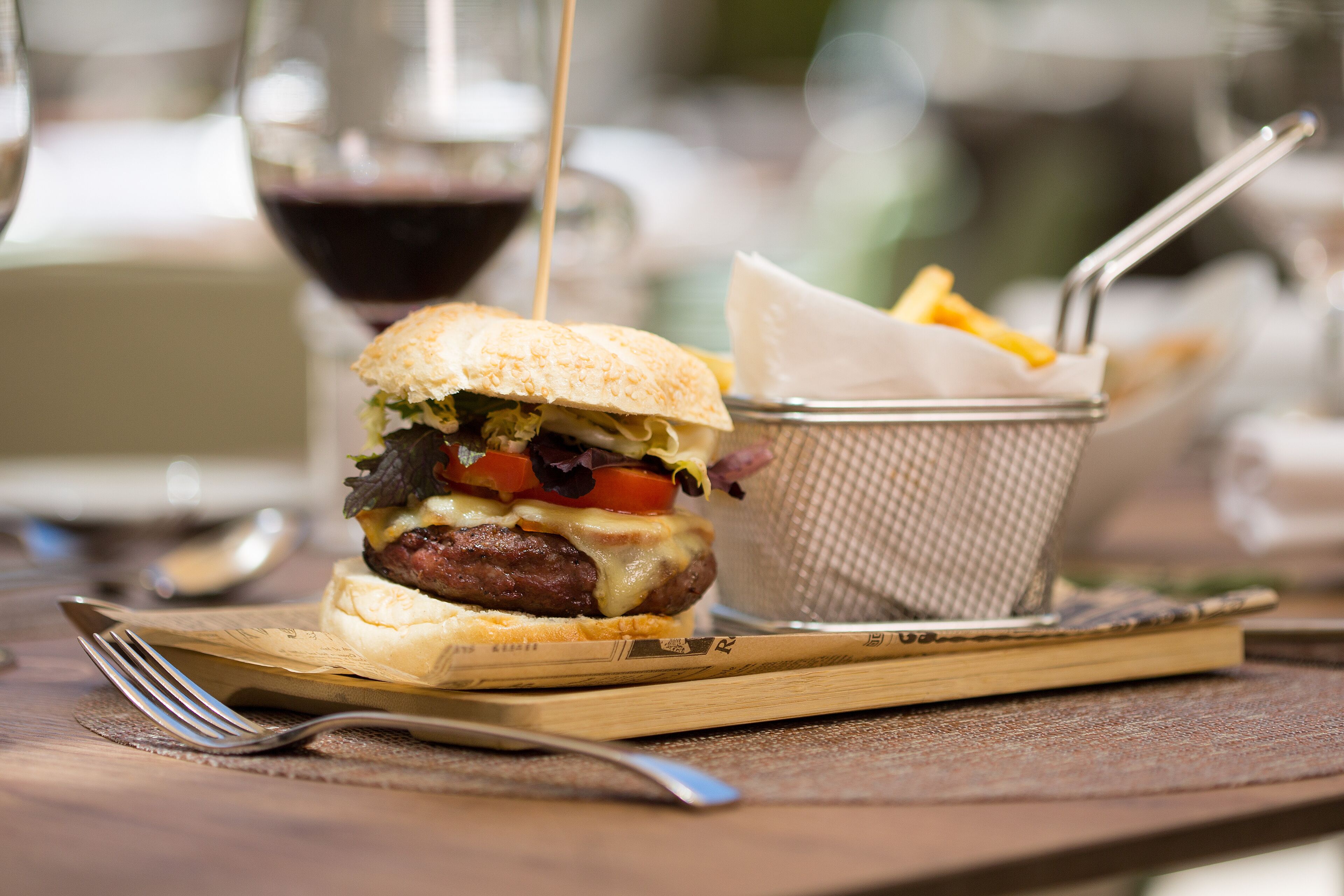 A meal with a burger, fries, and a drink on a wooden table.
