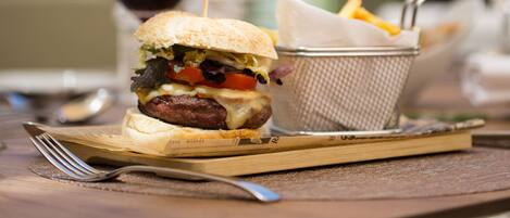 A meal with a burger, fries, and a drink on a wooden table.