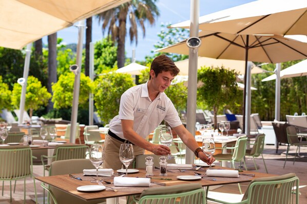 A restaurant setting with outdoor tables, chairs, and umbrellas. - Hotel Aimia (Sóller)