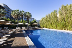 Relax by the serene pool surrounded by lush greenery and palm trees.