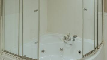 A modern bathroom with a glass-enclosed shower, a white bathtub, and a towel hanging on the tub.