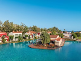 Un resort con villas coloridas, una piscina central y vistas al mar.