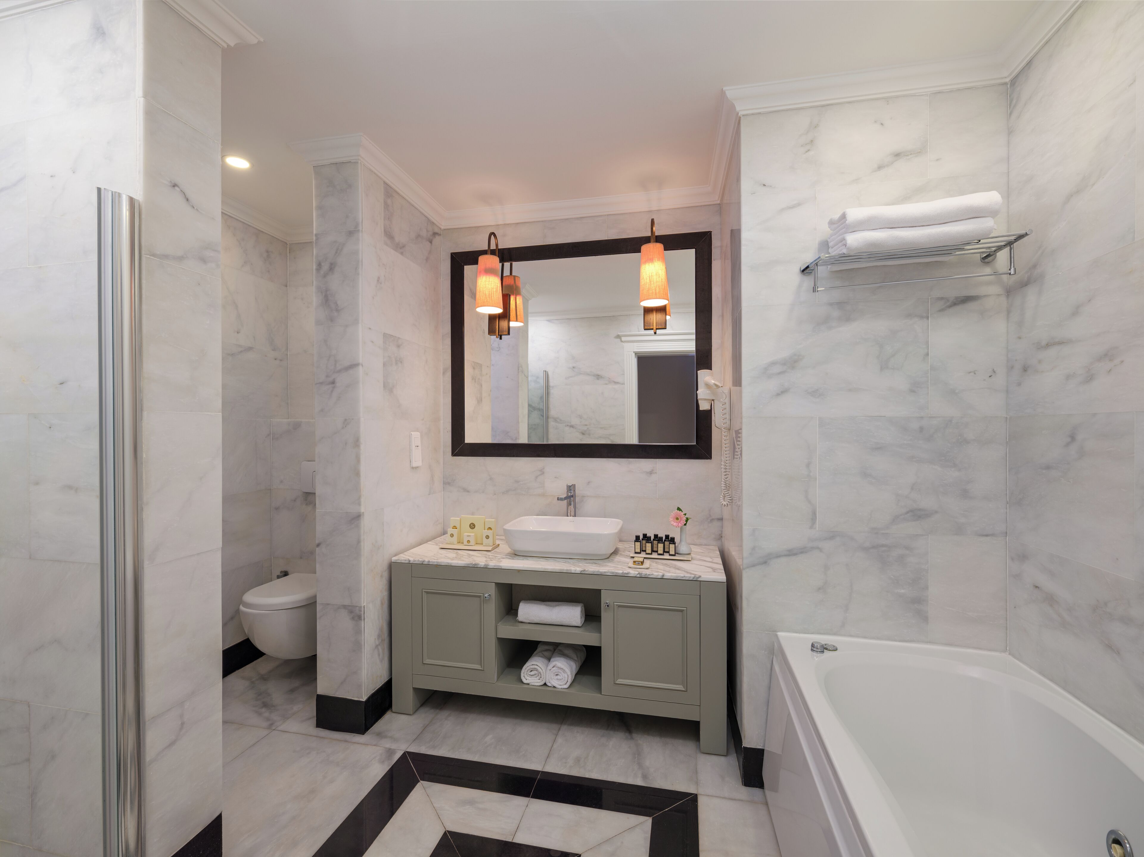 A modern bathroom with a white sink, vanity, and bathtub.