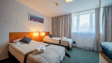 Habitación de hotel con dos camas, un cuadro en la pared, una ventana con cortinas y un cabecero.