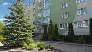A multi-story building with a green facade, a reception area, and a sign that reads "WITAMY WELCOME".