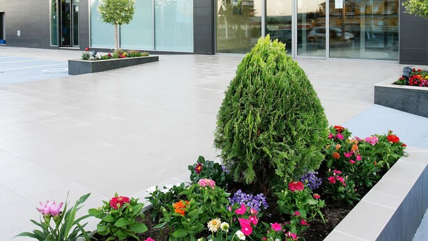 A hotel with a modern facade, a visible restaurant named 'Cateteria', and a landscaped garden area with various flowers. - BS Capitulaciones (Santa Fe)