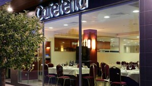 A restaurant with a glass facade, indoor seating, and a visible menu board. - BS Capitulaciones (Santa Fe)