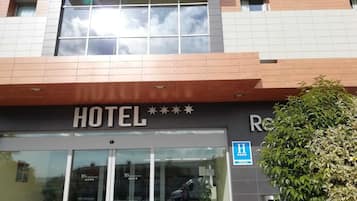L’entrée d’un hôtel, avec une enseigne indiquant « HÔTEL » et un panneau bleu signalant l’accessibilité aux personnes handicapées.