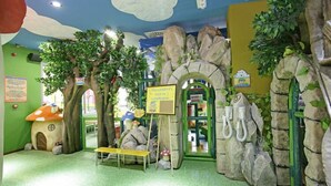 A children's play area with a treehouse, rock formations, and a bench. - BS Capitulaciones (Santa Fe)