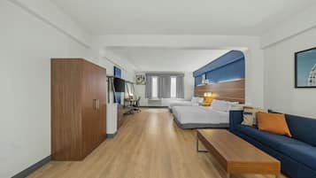 A hotel room with a wooden wardrobe, a sofa, a desk, and a bed.