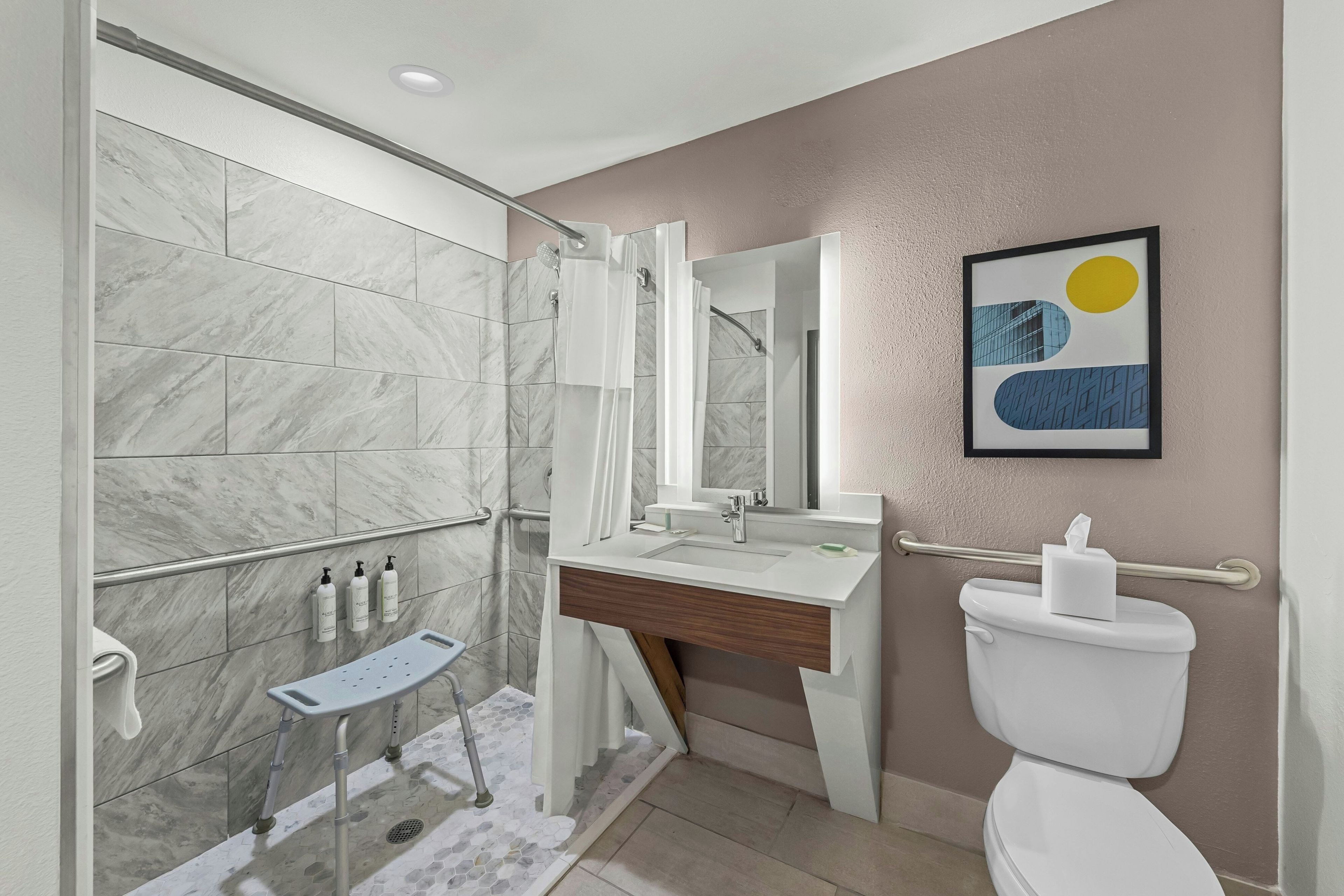A modern bathroom with a shower, toilet, sink, and a mirror.