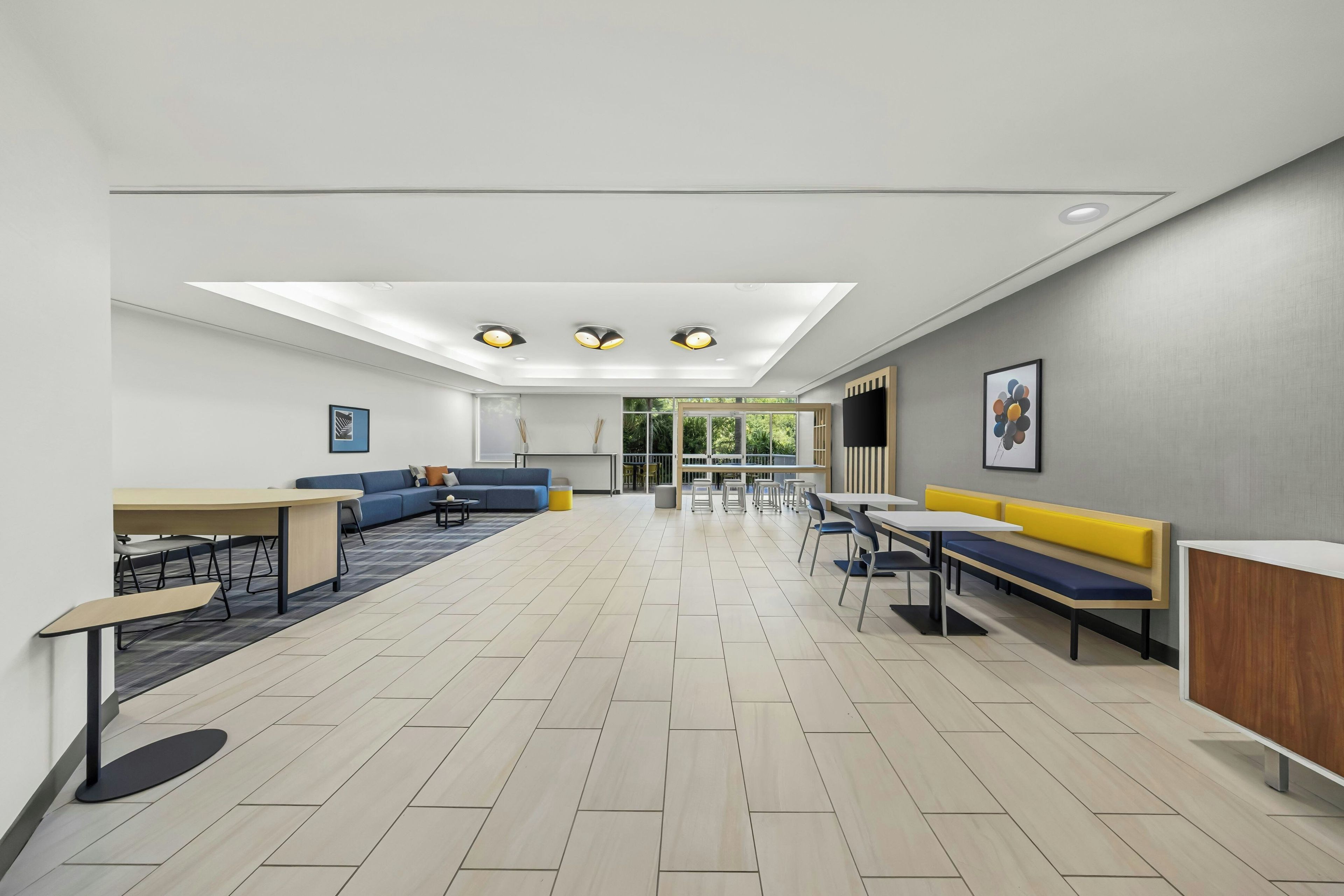 A modern interior with a dining area, sofas, and a reception desk.