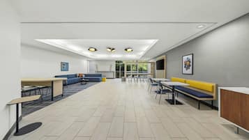 A modern interior with a dining area, sofas, and a reception desk.