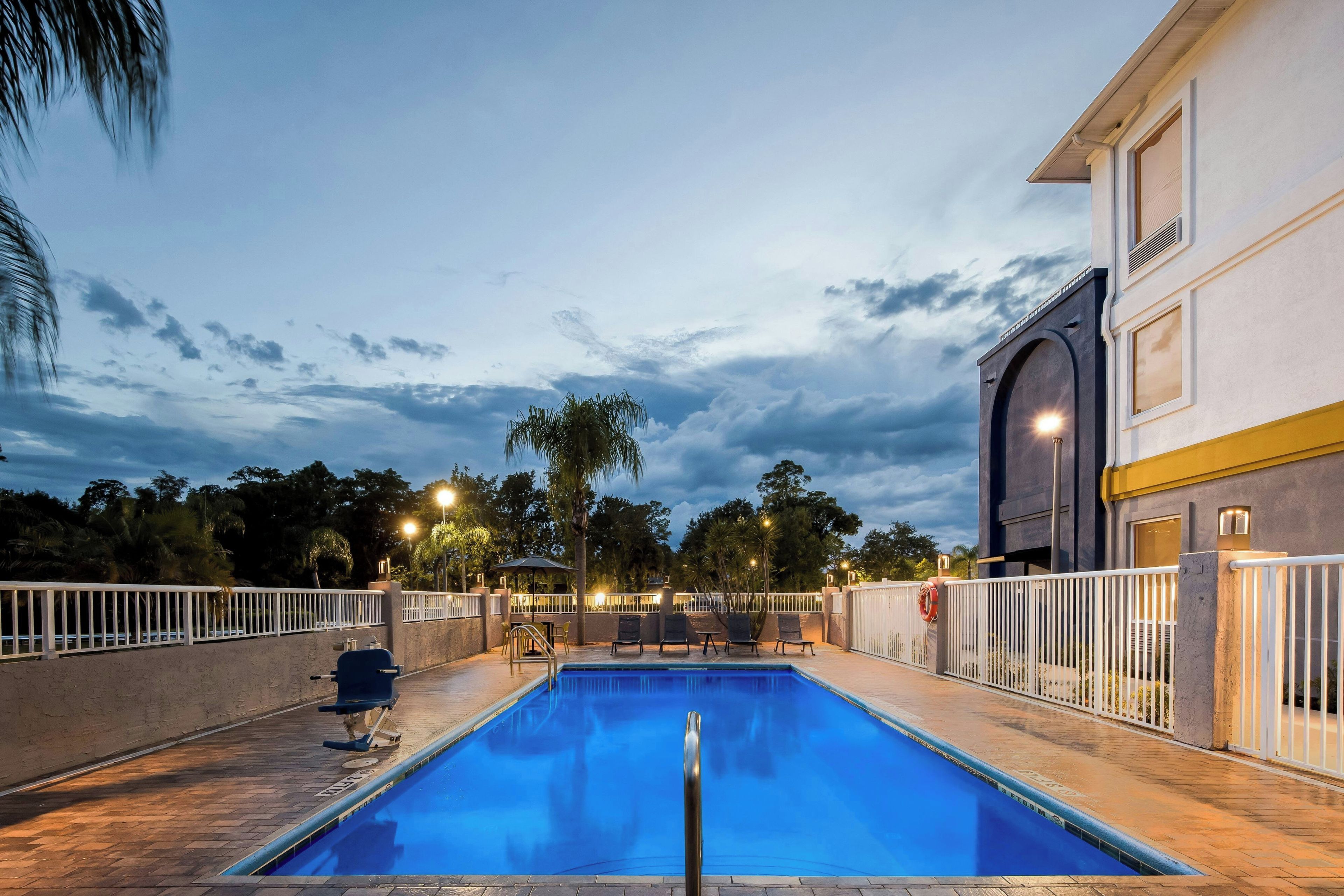 An outdoor swimming pool with a view of a building and trees in the background.