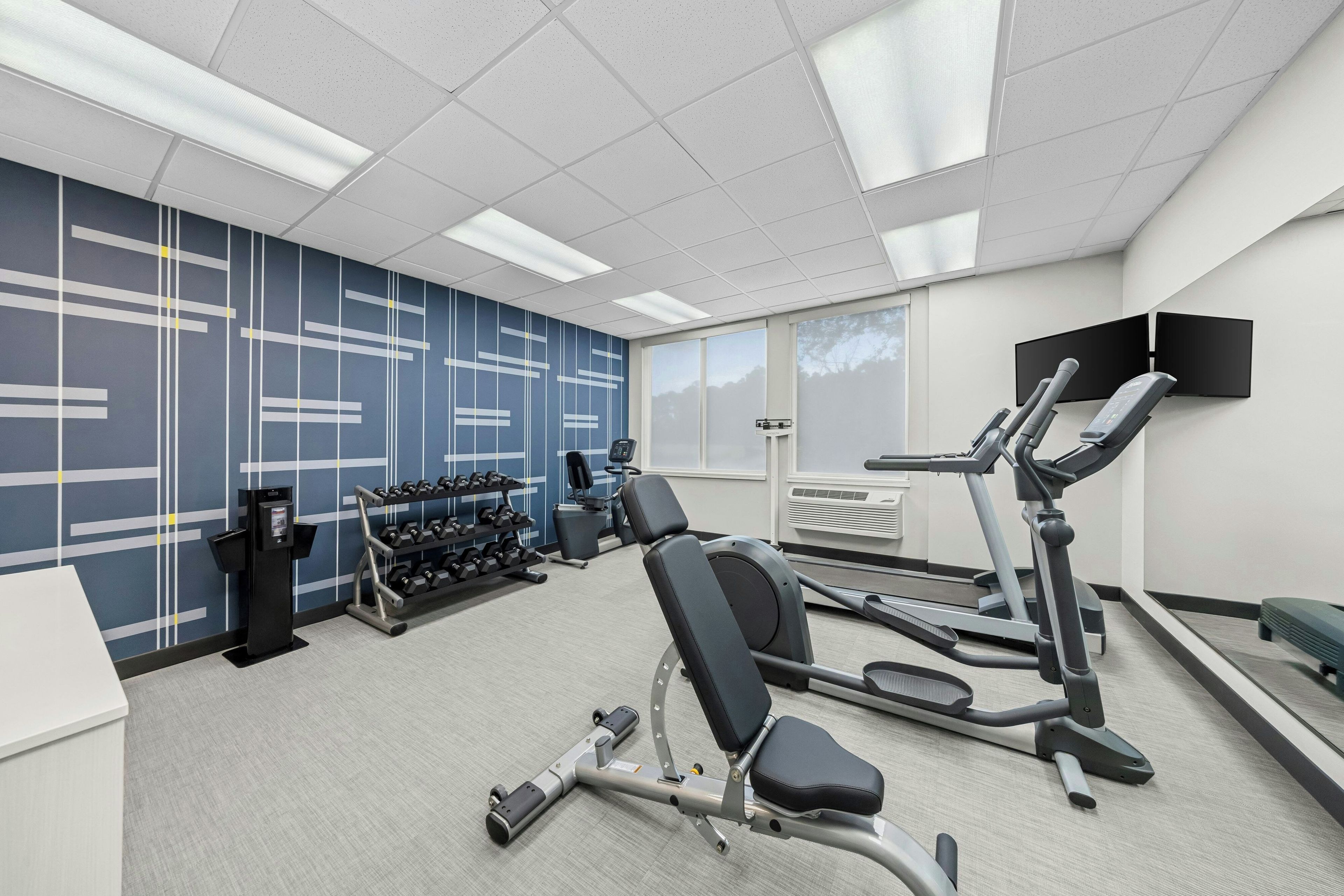 A gym with exercise equipment, a wall-mounted TV, and a window with a view.
