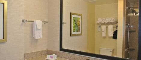 A hotel bathroom with a large mirror, a sink, and a shower.