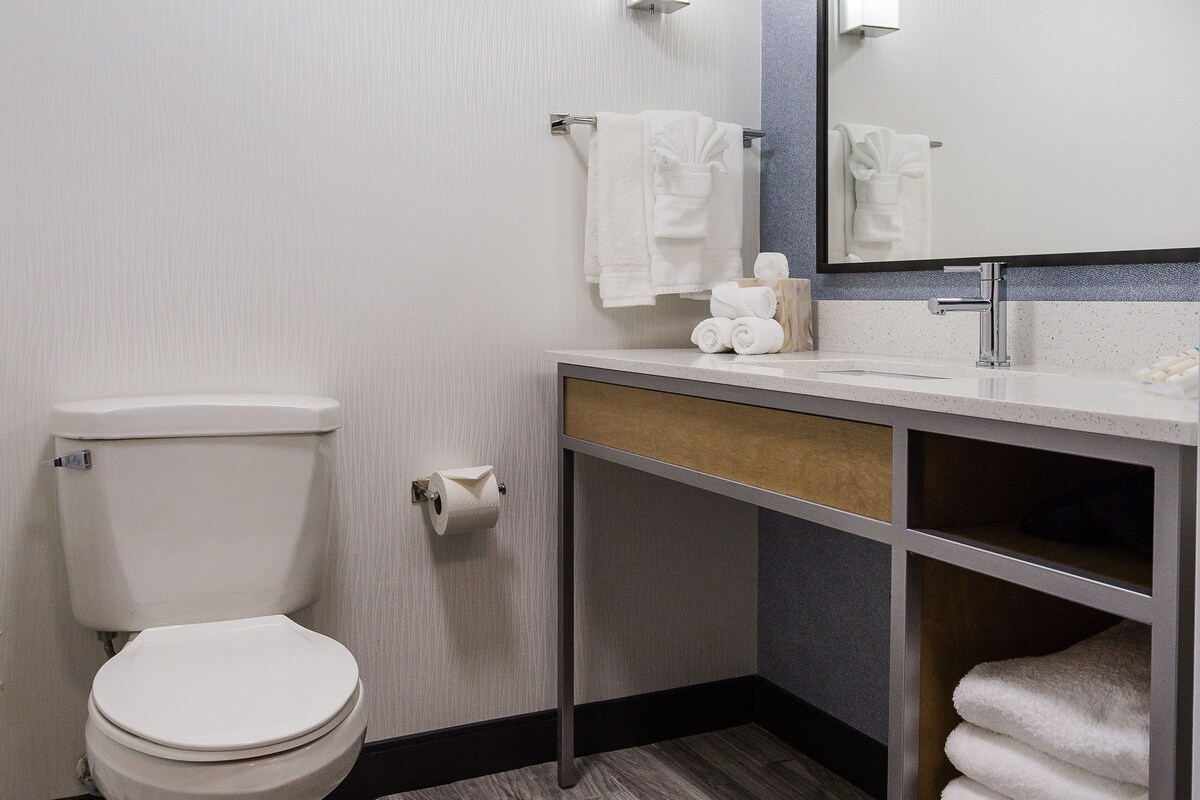 A modern bathroom with a toilet, sink, and mirror.