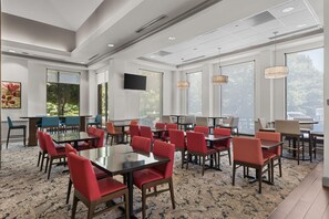 A conference room with multiple tables and chairs, large windows, and a flat-screen TV. - Hilton Garden Inn Atlanta Marietta (Atlanta)