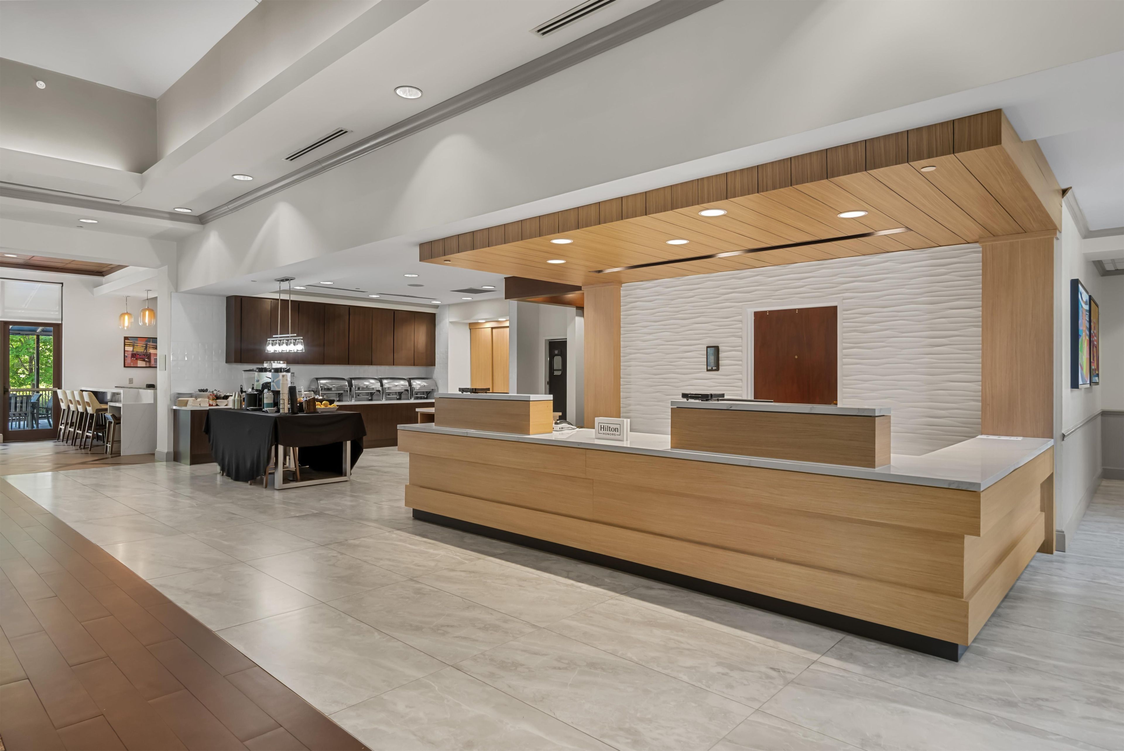 Un moderno vestíbulo de hotel con una recepción, un comedor y una cocina.