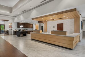Un hall d’hôtel moderne comprenant un comptoir d’accueil, un espace repas et une cuisine.