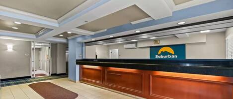 Un espace d’accueil avec un comptoir, une enseigne indiquant « Suburban », et une porte donnant sur une autre pièce.