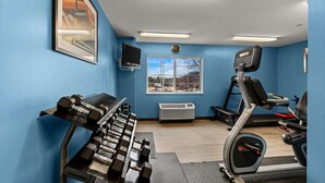 Un gimnasio con cinta de correr, banco de pesas y mancuernas.