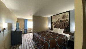 A hotel room with a large bed, a desk, a TV, and a painting of sunflowers on the wall. - Super 8 by Wyndham Independence KS (Independence)